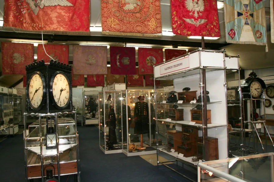 Interior of a museum with glass display cases, vintage clocks, and red and patterned banners hanging from the ceiling