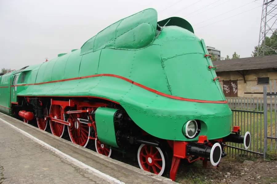 Green steam locomotive with red wheels and trim on a railway platform