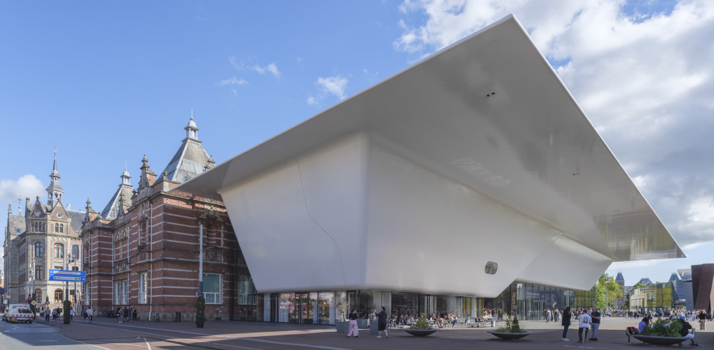 Moderne, hoekige witte uitbreiding van het Stedelijk Museum Amsterdam met historisch roodstenen gebouw, mensen op het plein, blauwe lucht