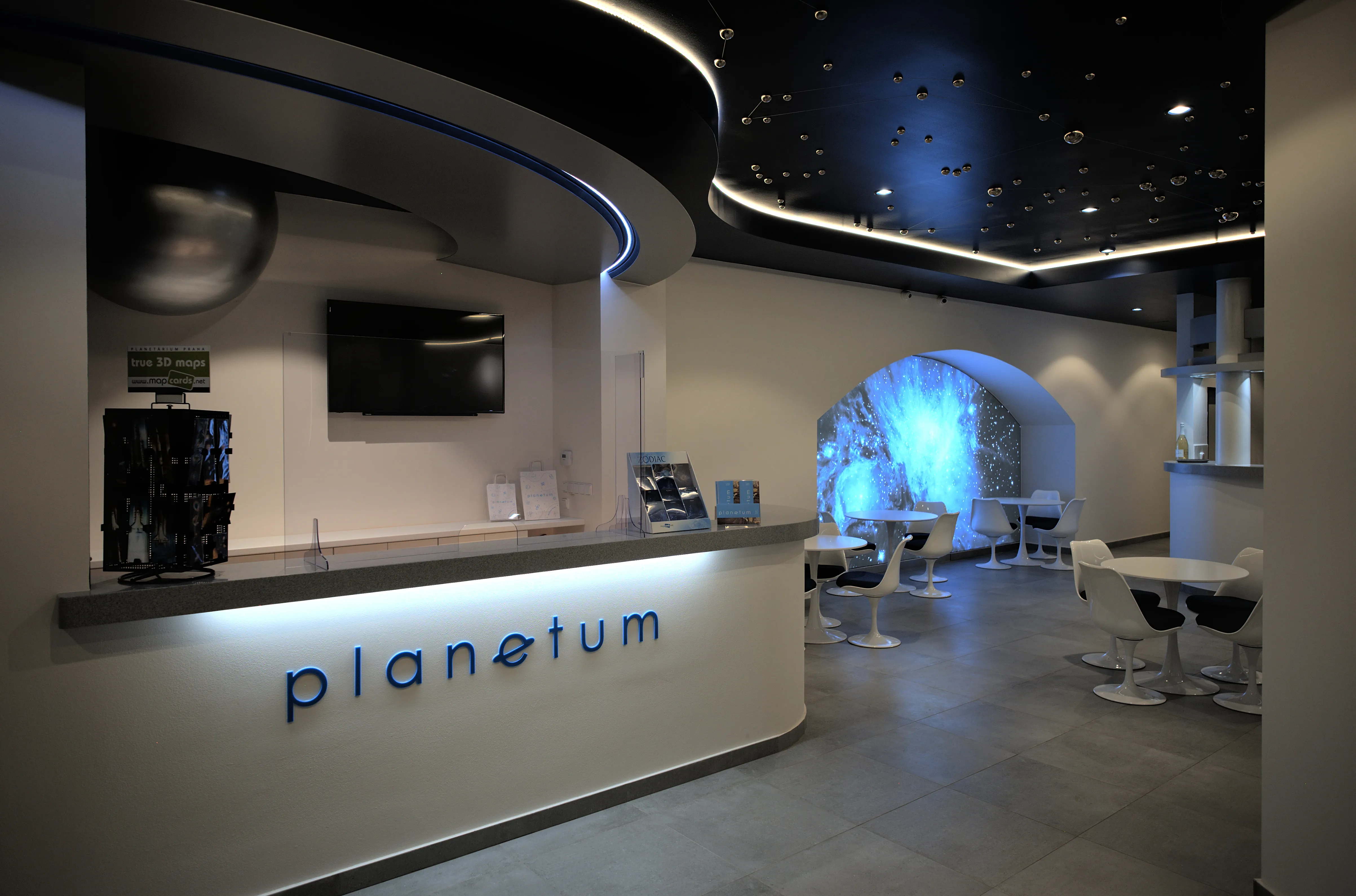 interior moderno del Observatorio Štefánik con un mostrador de recepción etiquetado como 'planetum', techo estrellado y un arco azul brillante