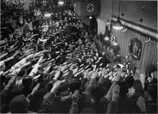 foto histórica en blanco y negro de una multitud realizando el saludo nazi con banderas de esvástica