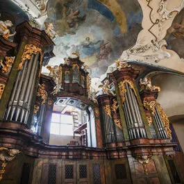 Barokowe organy piszczałkowe ze złotymi detalami i malowanym freskiem na suficie w kościele