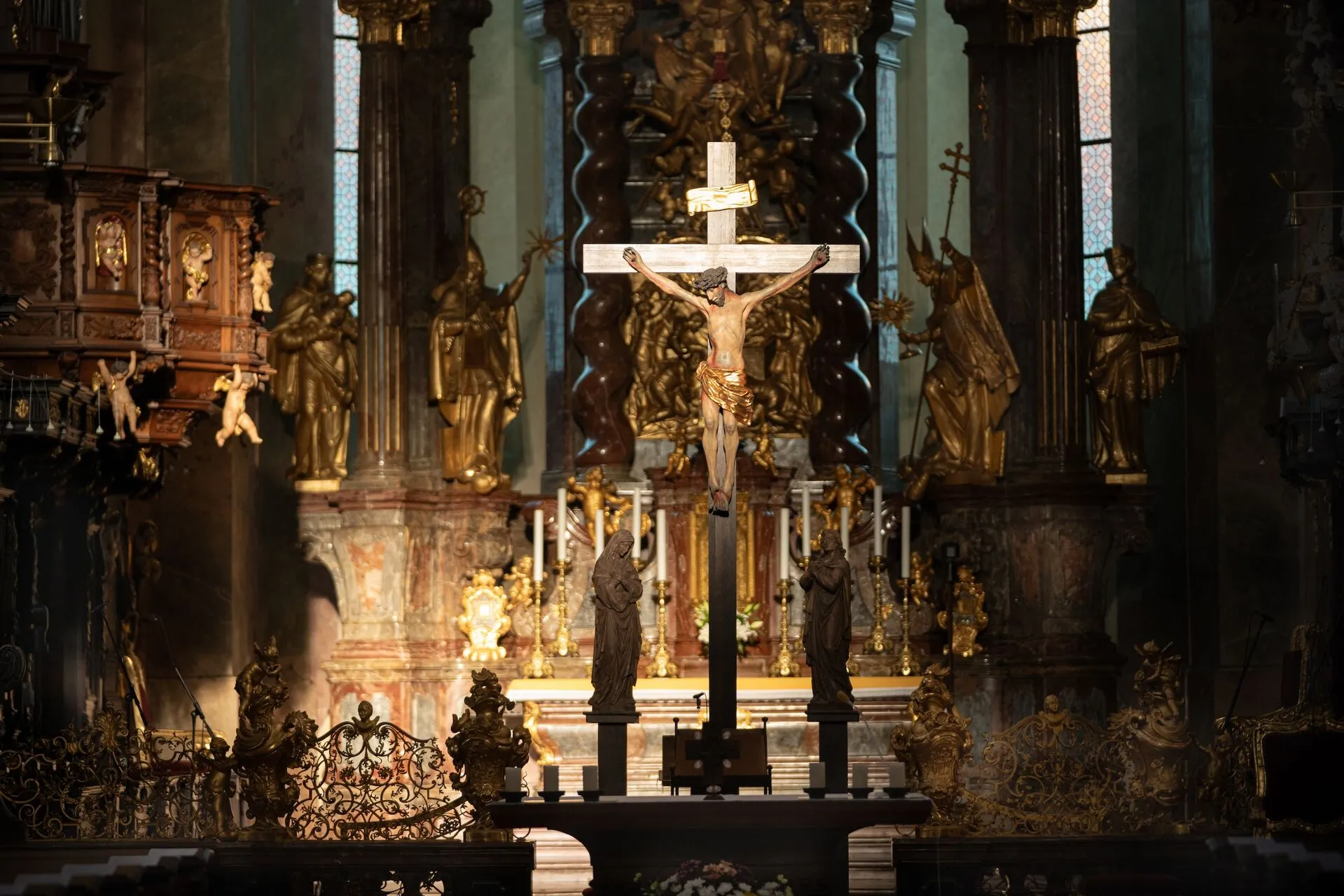 centralny krucyfiks ze złotymi posągami i ozdobnymi ołtarzami we wnętrzu kościoła barokowego