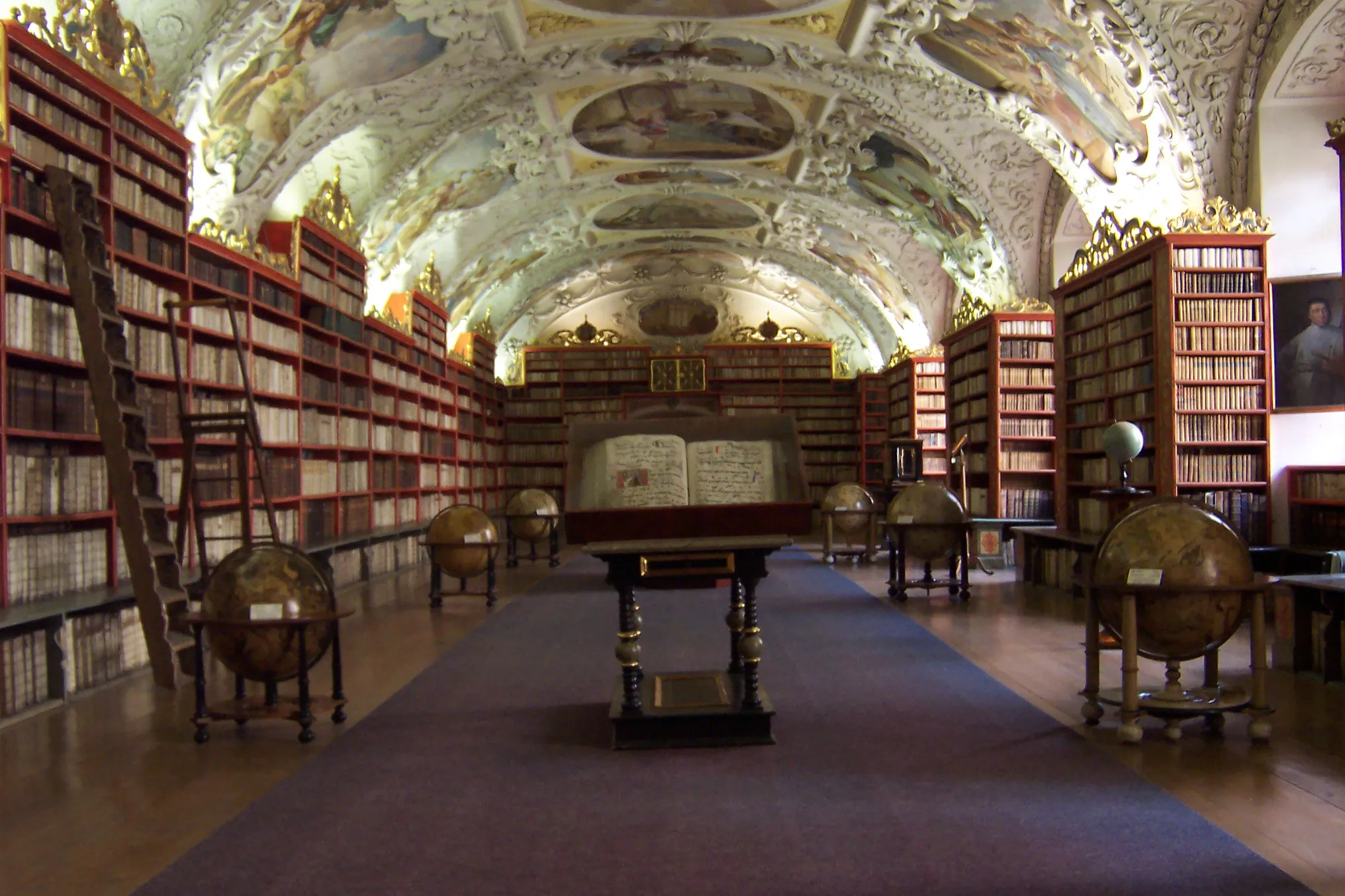 Ornate baroque library with high arched ceilings, frescoes, and rows of bookshelves