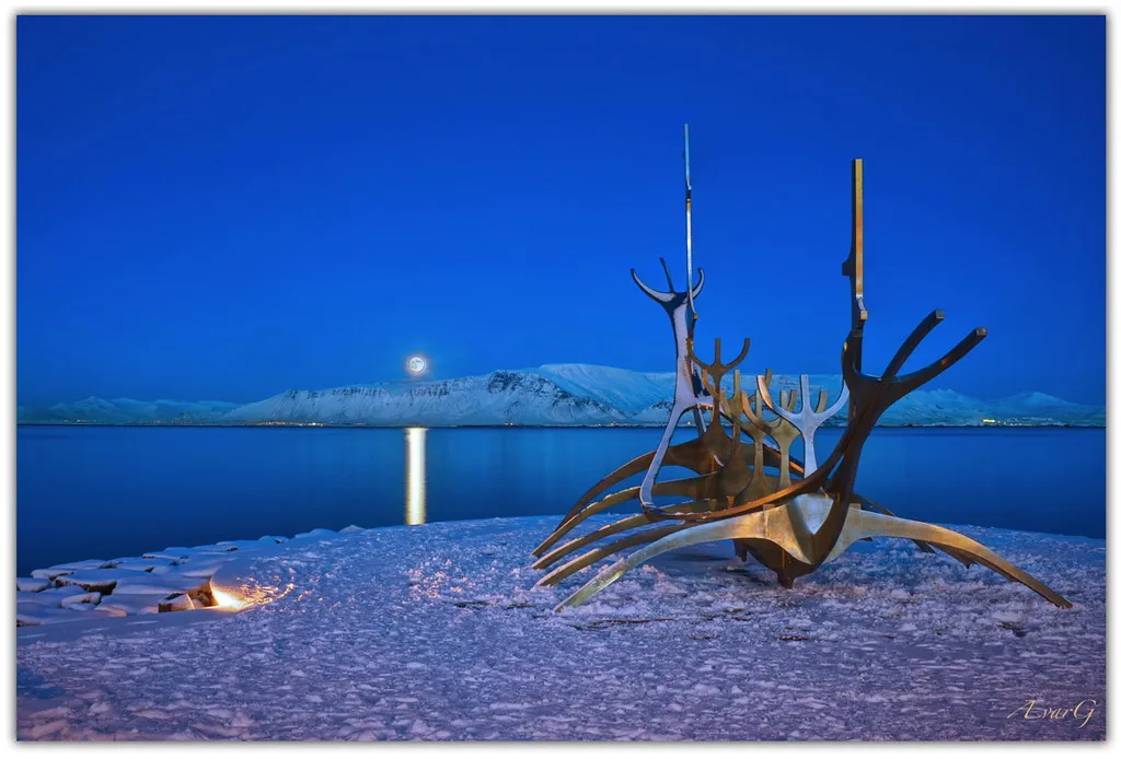 Rzeźba ze stali nierdzewnej Sun Voyager na nabrzeżu Reykjavíku nocą, z pełnią księżyca odbijającą się w morzu i pokrytą śniegiem ziemią