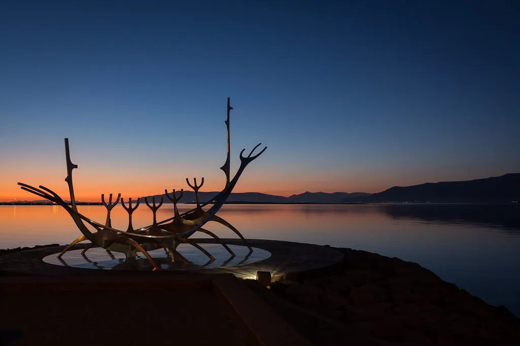 Rzeźba ze stali nierdzewnej Sun Voyager na tle żywego pomarańczowo-niebieskiego zachodu słońca nad nabrzeżem Reykjavíku