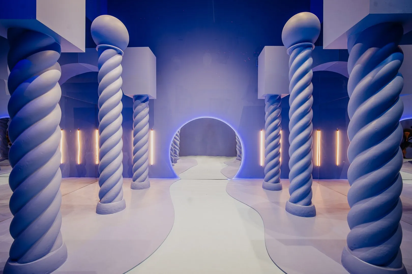 Blauw-witte gedraaide zuilen in een futuristische binnenruimte met een gloeiende boog