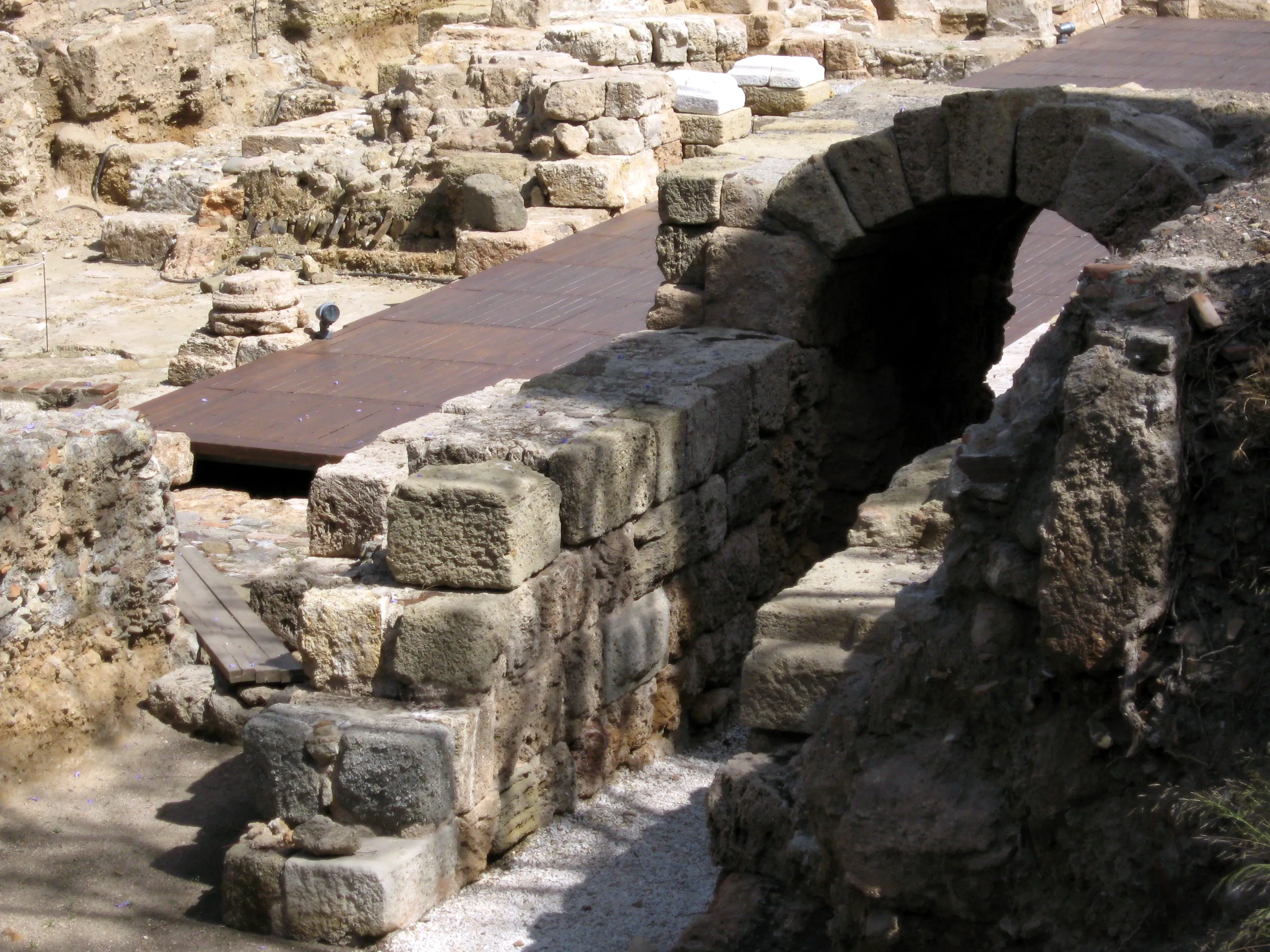 Kamienne ruiny rzymskiego teatru z łukowatym przejściem i zwietrzałymi blokami wapienia na stanowisku archeologicznym