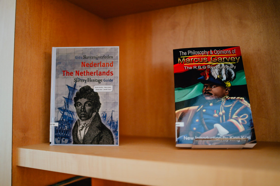 Dos libros en un estante de madera: 'The Netherlands: A Black History Guide' y 'The Philosophy & Opinions of Marcus Garvey', expuestos en The Black Archives
