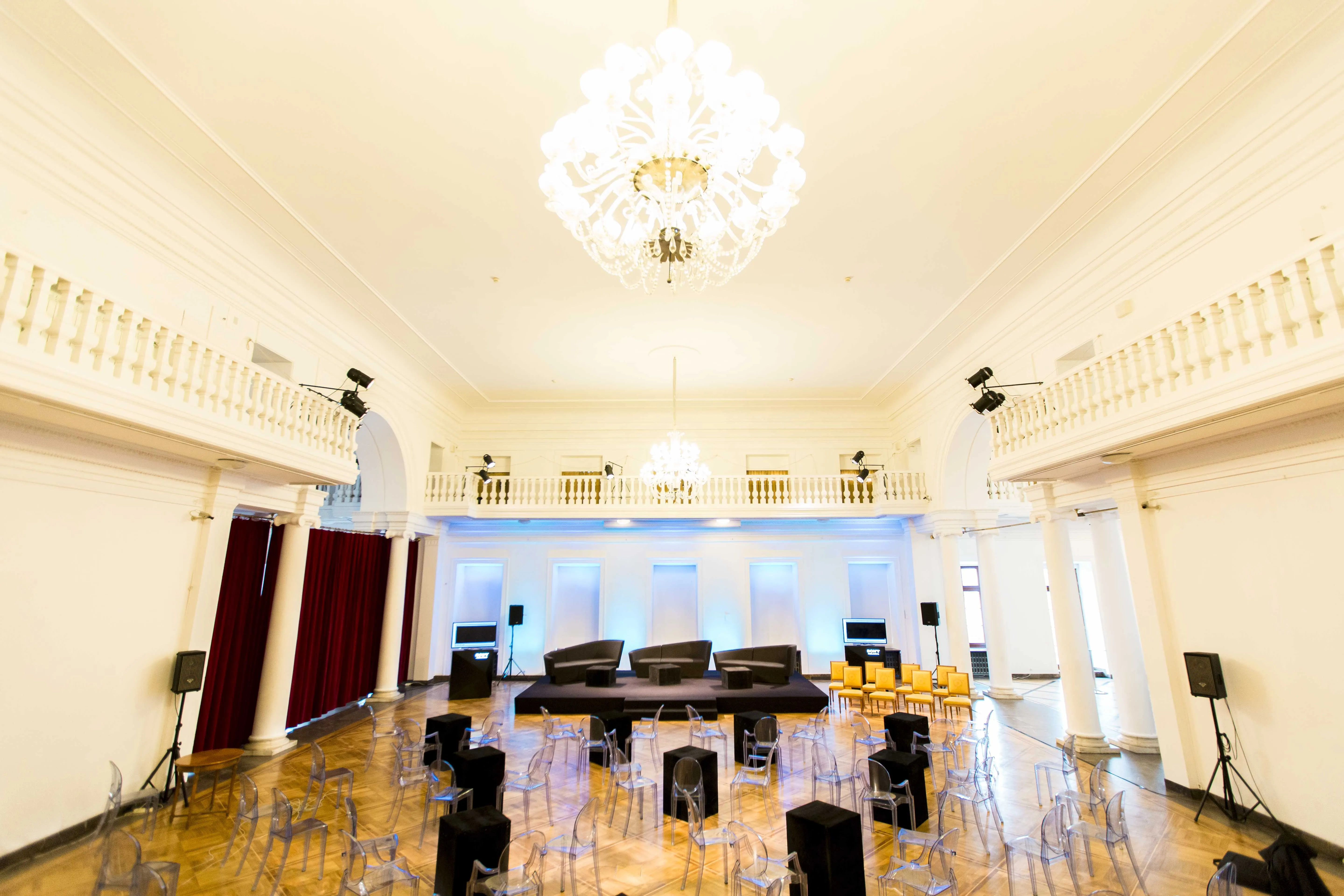Large interior hall with chandelier, white balconies, and stage setup