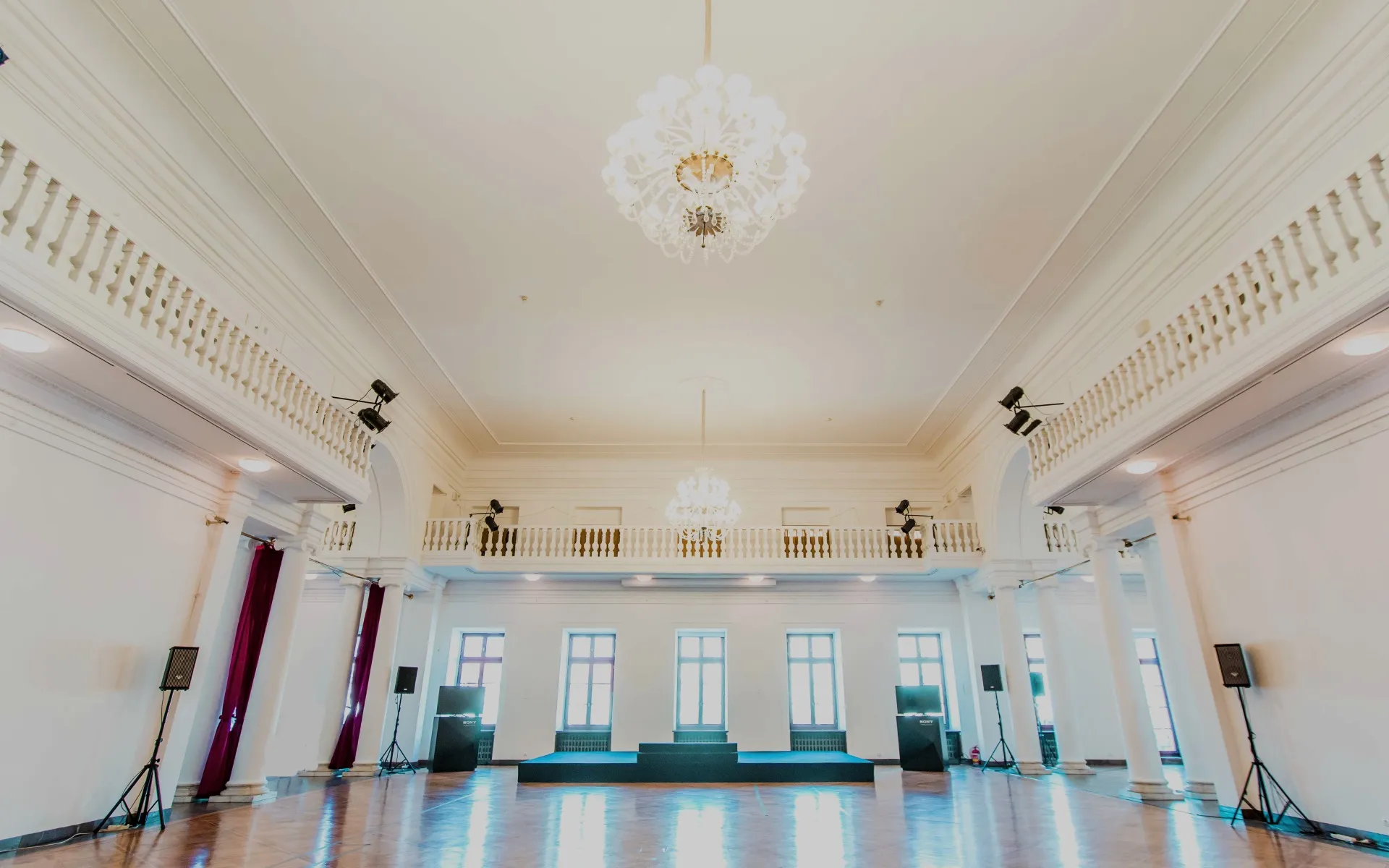 Large interior hall with white walls, high ceilings, and a chandelier