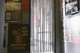 Interieur van Third Man Museum met ingelijste documenten, een filmposter en een kralengordijn