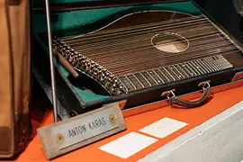 Een citerinstrument in een kist met een plaquette waarop 'ANTON KARAS' staat.