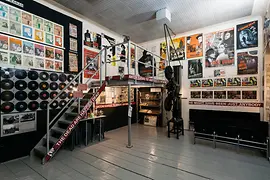 Interieur van het Third Man Museum met muren bedekt met posters en platen, een trap en vitrines