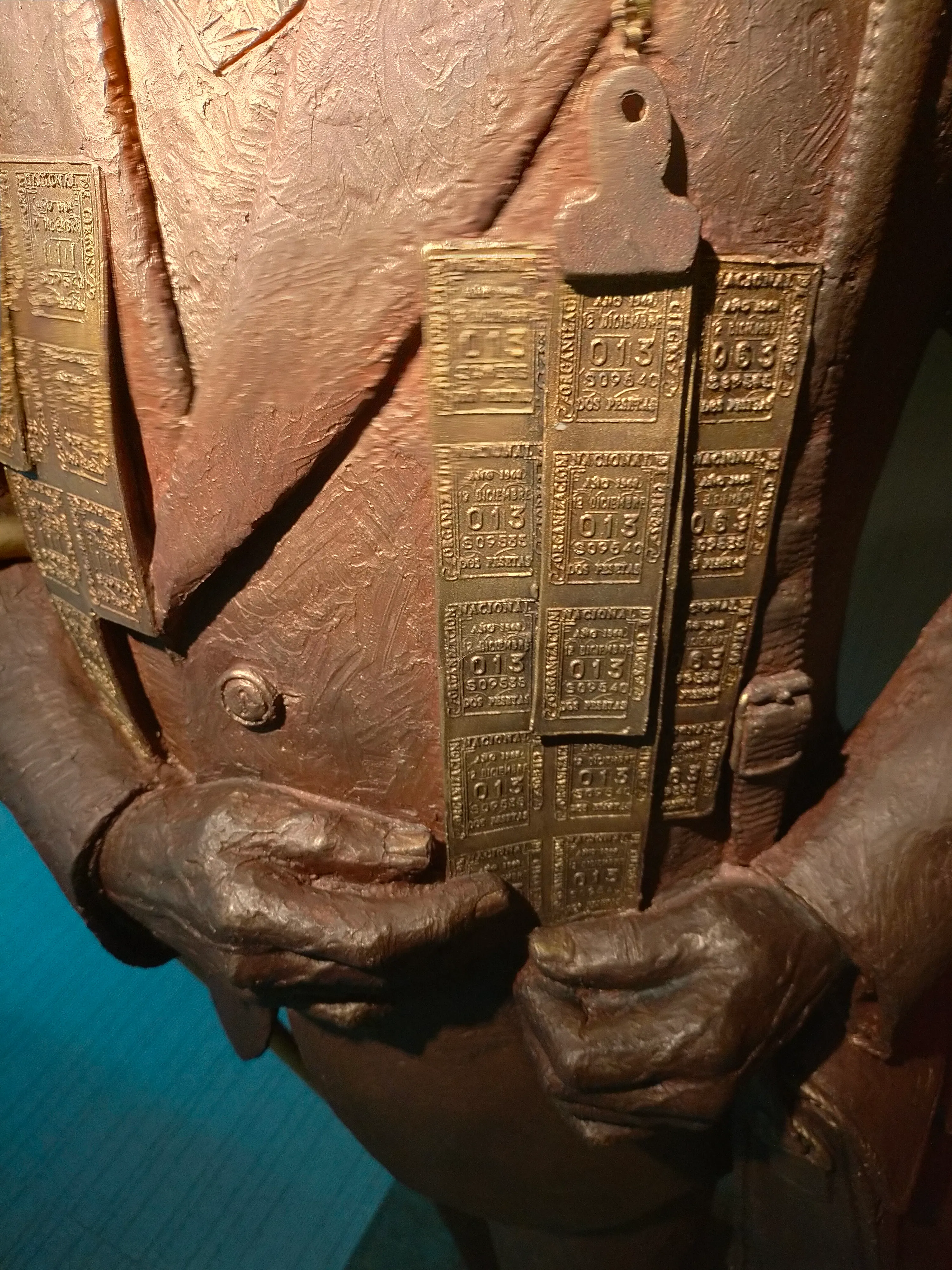 primer plano de una escultura de bronce con manos y placas grabadas con texto en braille