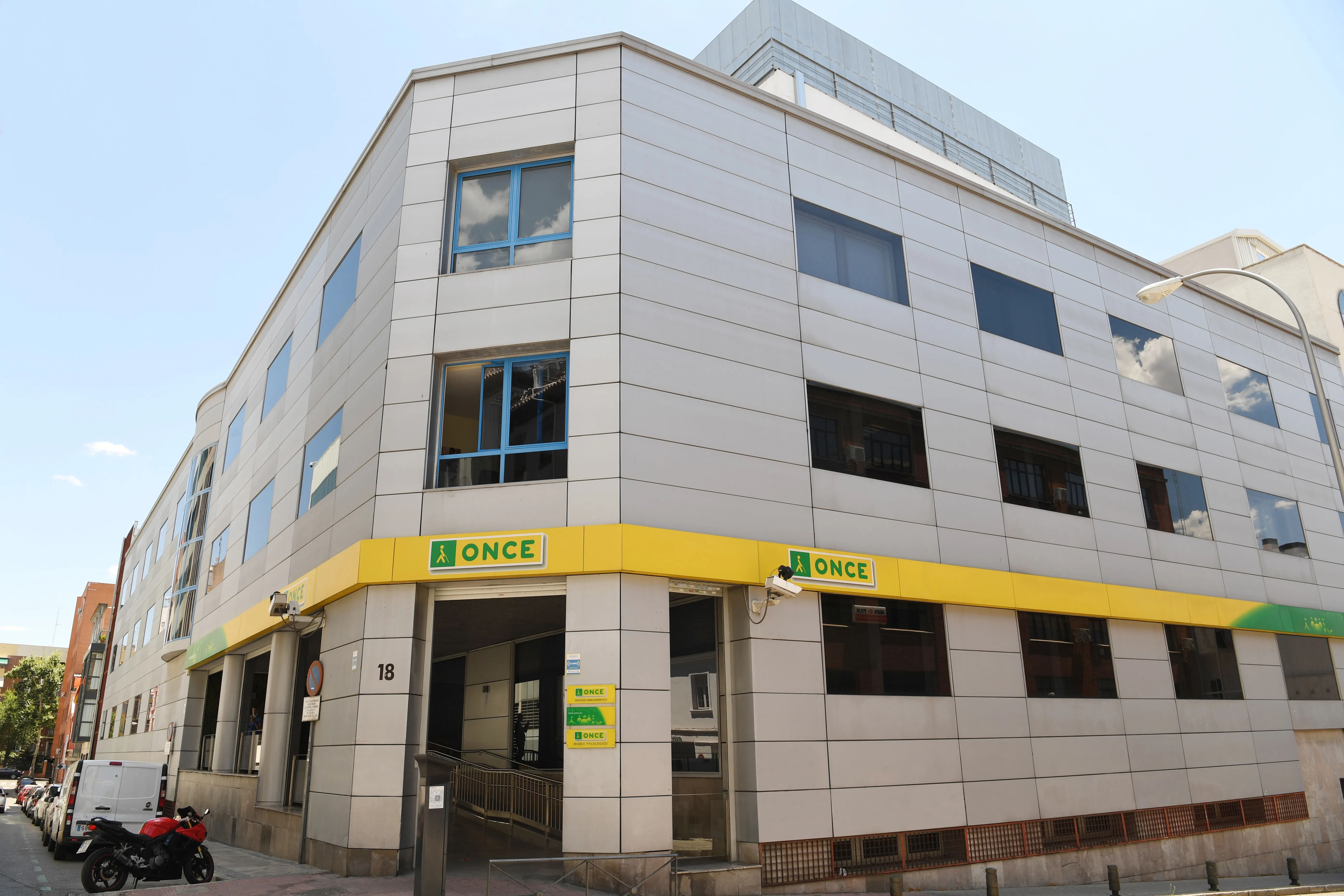 edificio moderno con fachada gris y letrero amarillo de ONCE en la esquina de la calle