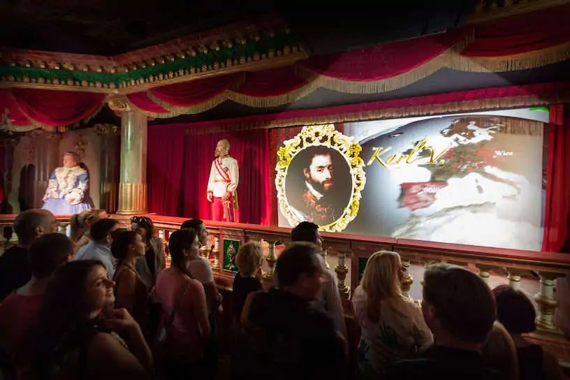 Publiczność oglądająca pokaz multimedialny z figurami animatronicznymi i dużym ekranem w sali teatralnej