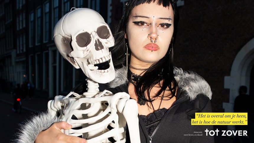 Persona con ropa oscura y abrigo forrado de piel sosteniendo un accesorio de esqueleto blanco; cita de texto en holandés y marca 'tot ZOVER' visibles en cuadro amarillo.