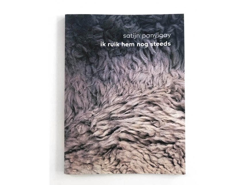 Portada de libro con fondo texturizado similar a la lana en tonos grises y morados, con el texto blanco 'satijn panyigay ik ruik hem nog steeds'