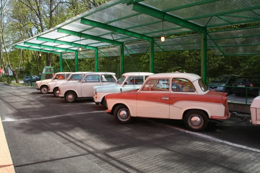 Coches Trabant vintage aparcados bajo un dosel metálico verde en el Museo Trabant Motol