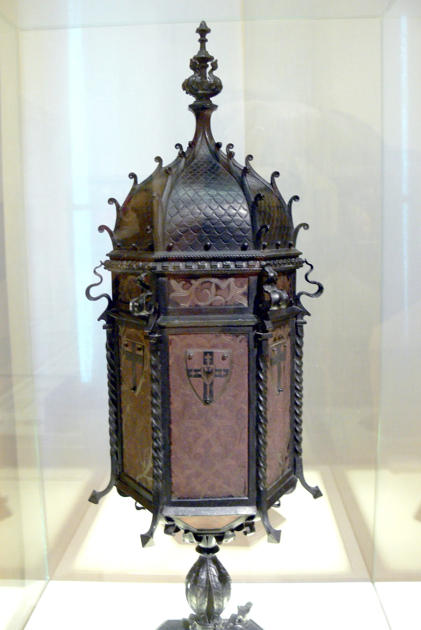 Een sierlijke, donker metalen kist met een koepelvormig deksel en decoratieve elementen, tentoongesteld in een vitrine
