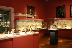Rood-muren museuminterieur met glazen vitrines met artefacten en ingelijste portretten aan de muur