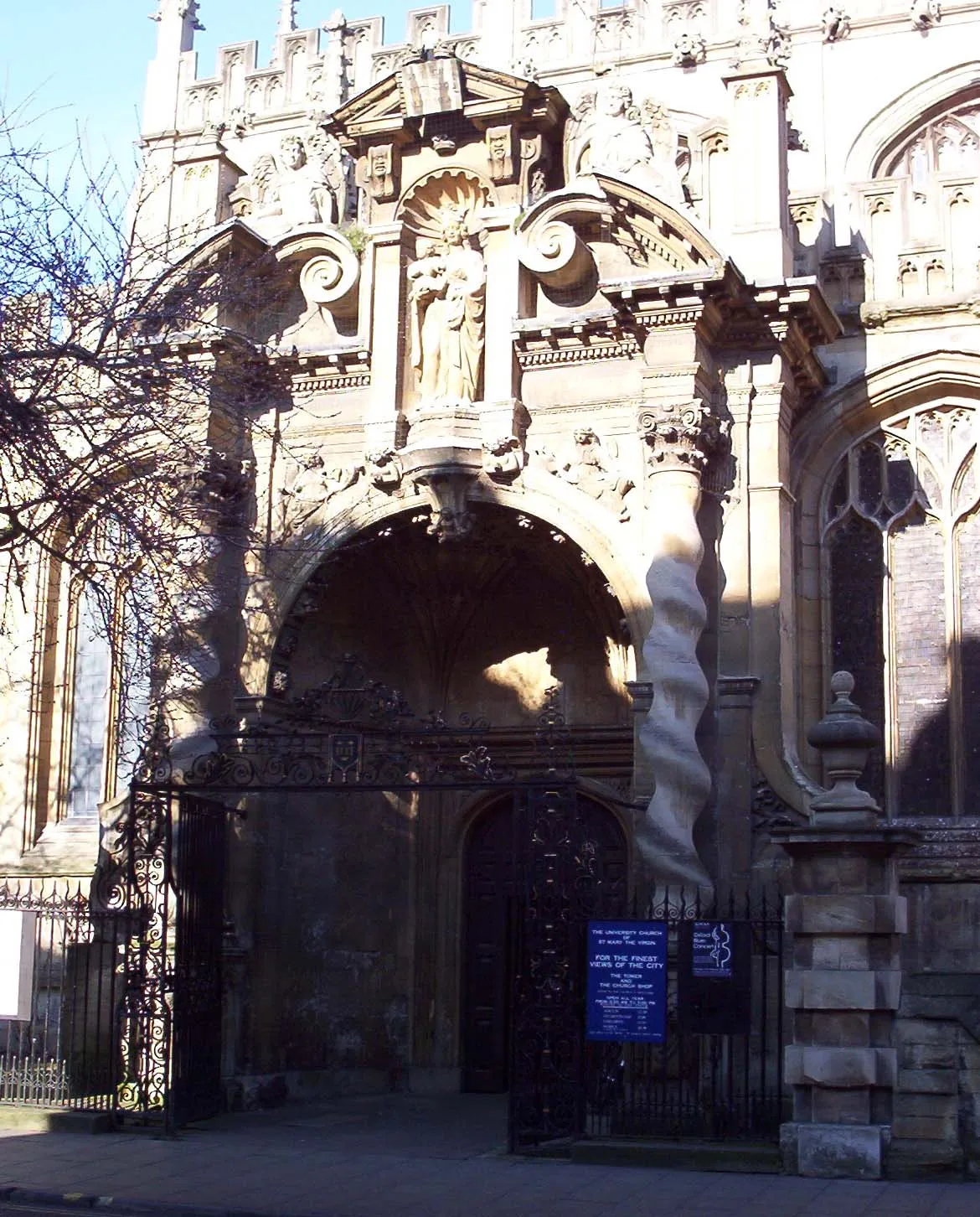 Ornado pórtico de piedra barroco de la University Church of St Mary the Virgin, que presenta columnas salomónicas, estatuas y una gran entrada arqueada.