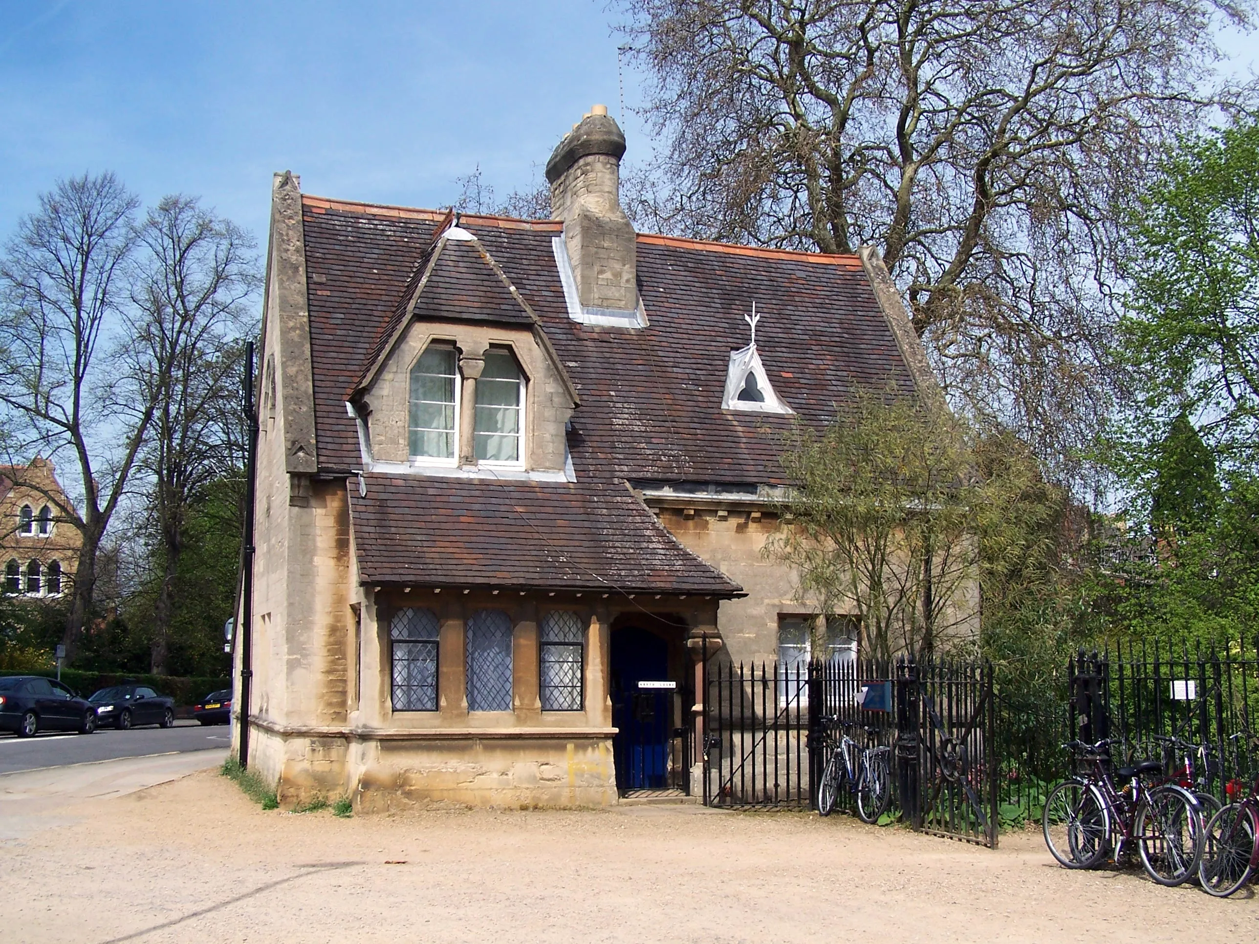 Stenen lodgegebouw met pannendak, blauwe deur en fietsen geparkeerd bij de ingang van de Oxford University Parks