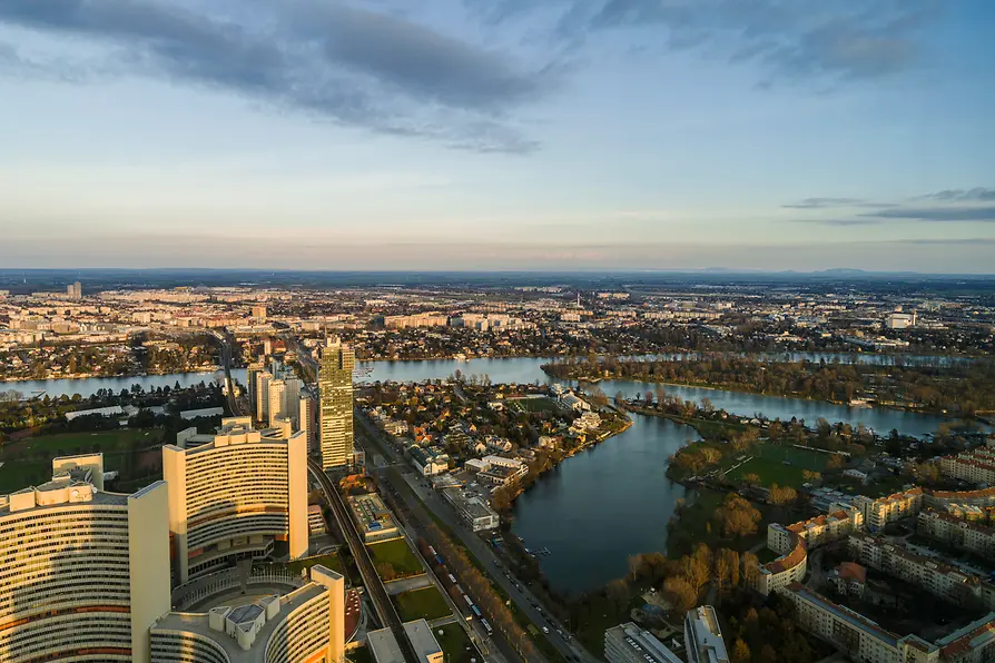 Luchtfoto van UNO City met moderne gebouwen, een rivier en een stadsgezicht onder een deels bewolkte hemel