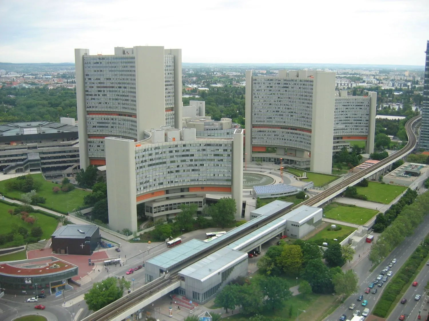 Luchtfoto van moderne gebouwen in het Vienna International Centre met omliggende groen en een treinspoor