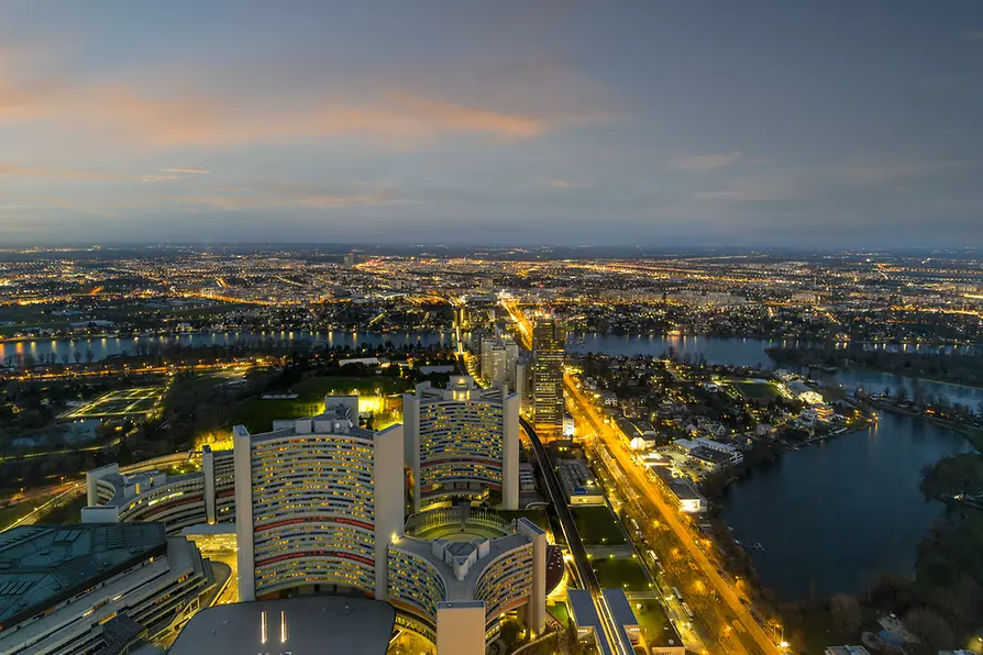 Luchtfoto van UNO City met verlichte gebouwen en waterwegen bij schemering