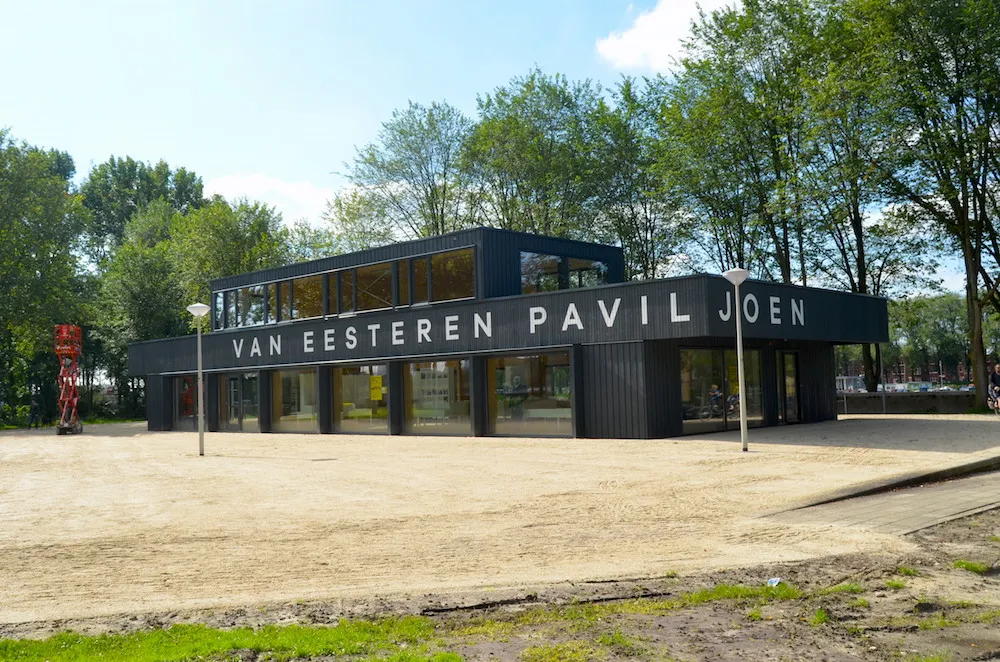 Edificio moderno de color negro con grandes ventanales y un letrero que dice VAN EESTEREN PAVILJOEN