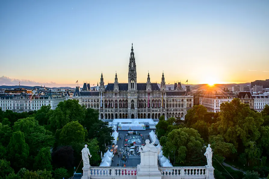 Vienna City Hall at sunset with a prominent central spire and surrounding greenery