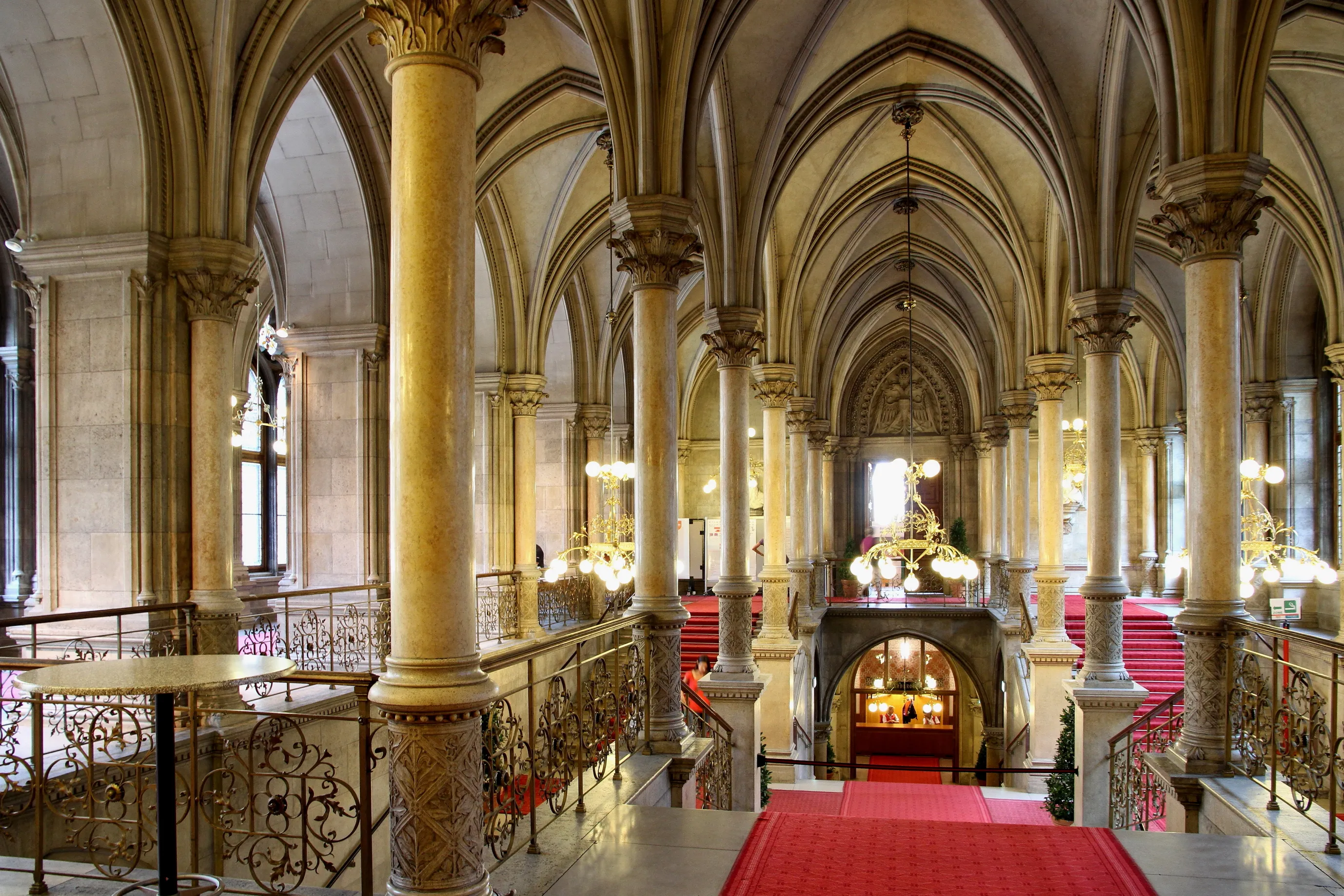 Interior of Vienna City Hall with arched ceilings, stone columns, and a red carpeted staircase