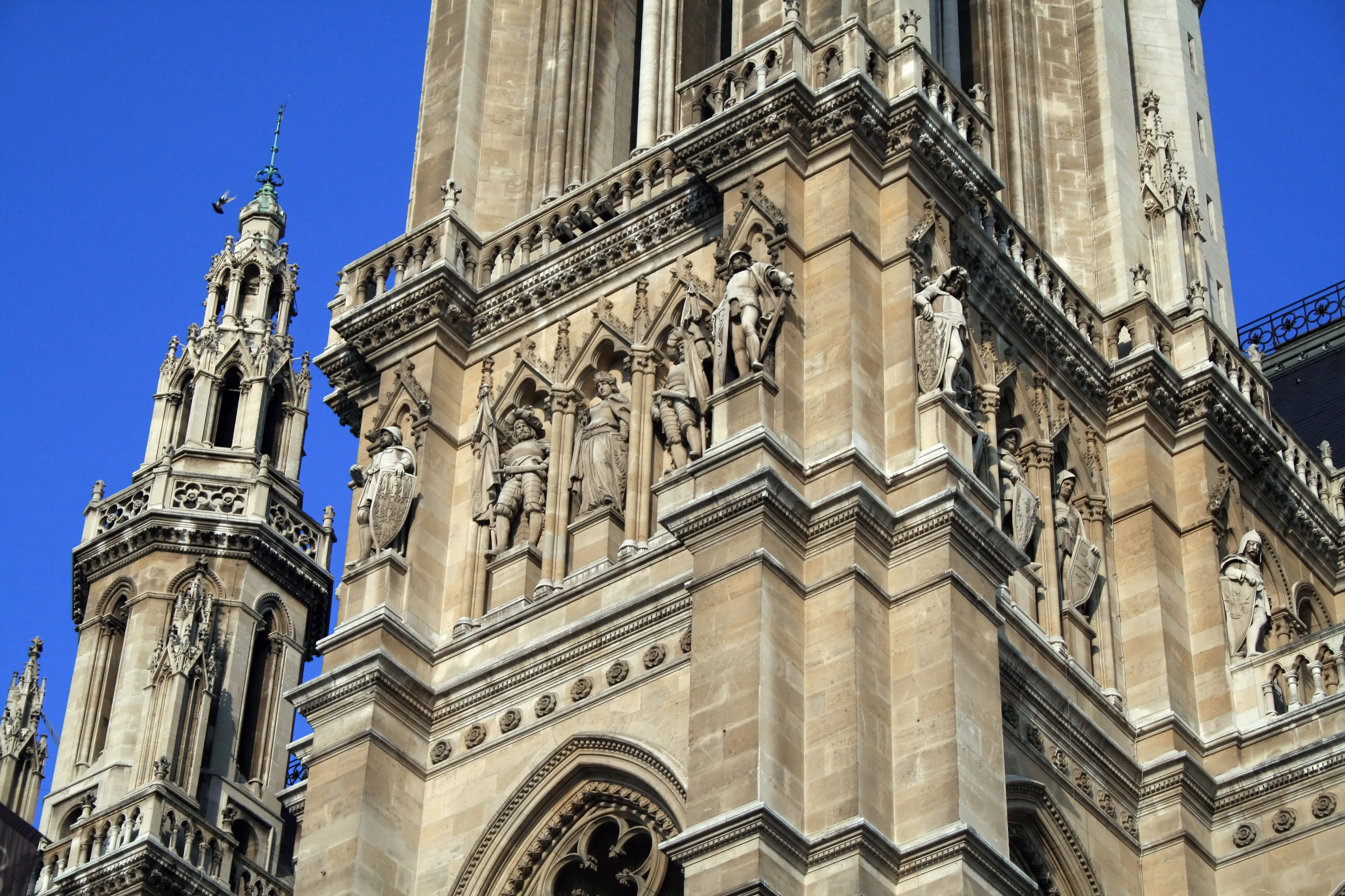 Close-up of stone carvings and statues on the facade of Vienna City Hall under a blue sky