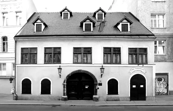 foto en blanco y negro de un edificio con puertas arqueadas, ventanas abuhardilladas y faroles