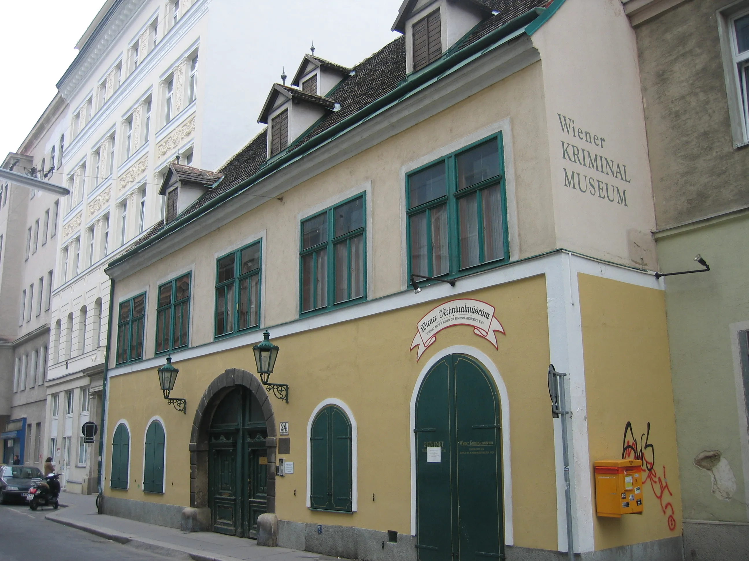 Edificio amarillo con ventanas y puertas verdes, letrero que dice Wiener Kriminalmuseum en la fachada