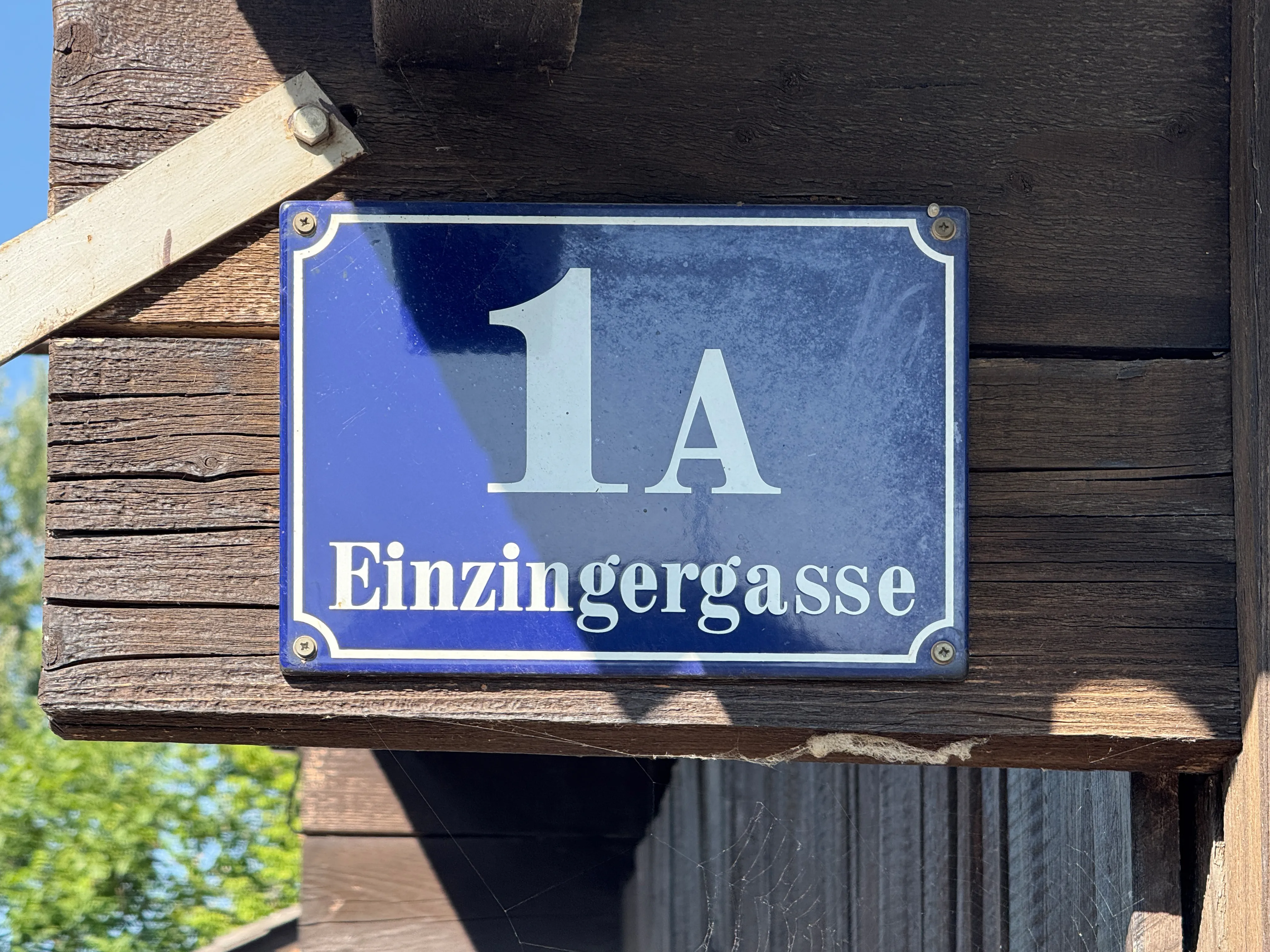 cartel azul con texto blanco 1A Einzingergasse en una pared de madera