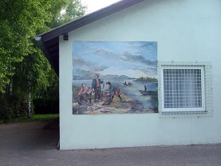 Mural de pescadores y escena de río en la pared exterior de un edificio