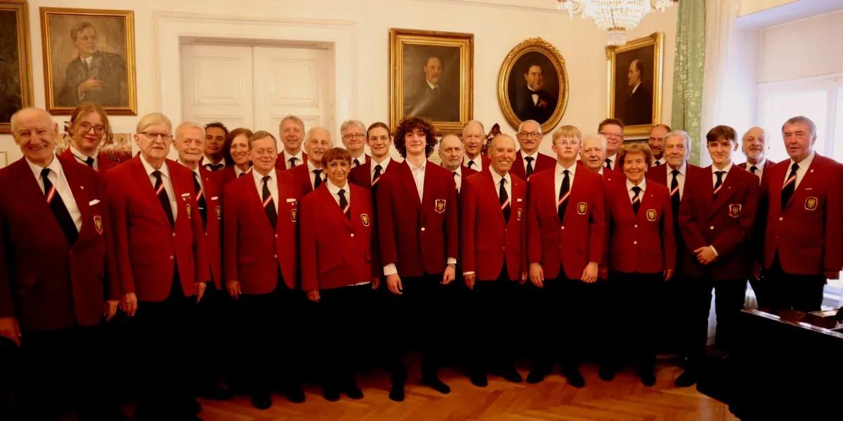 Grupo de personas con chaquetas rojas de pie en una sala con retratos enmarcados