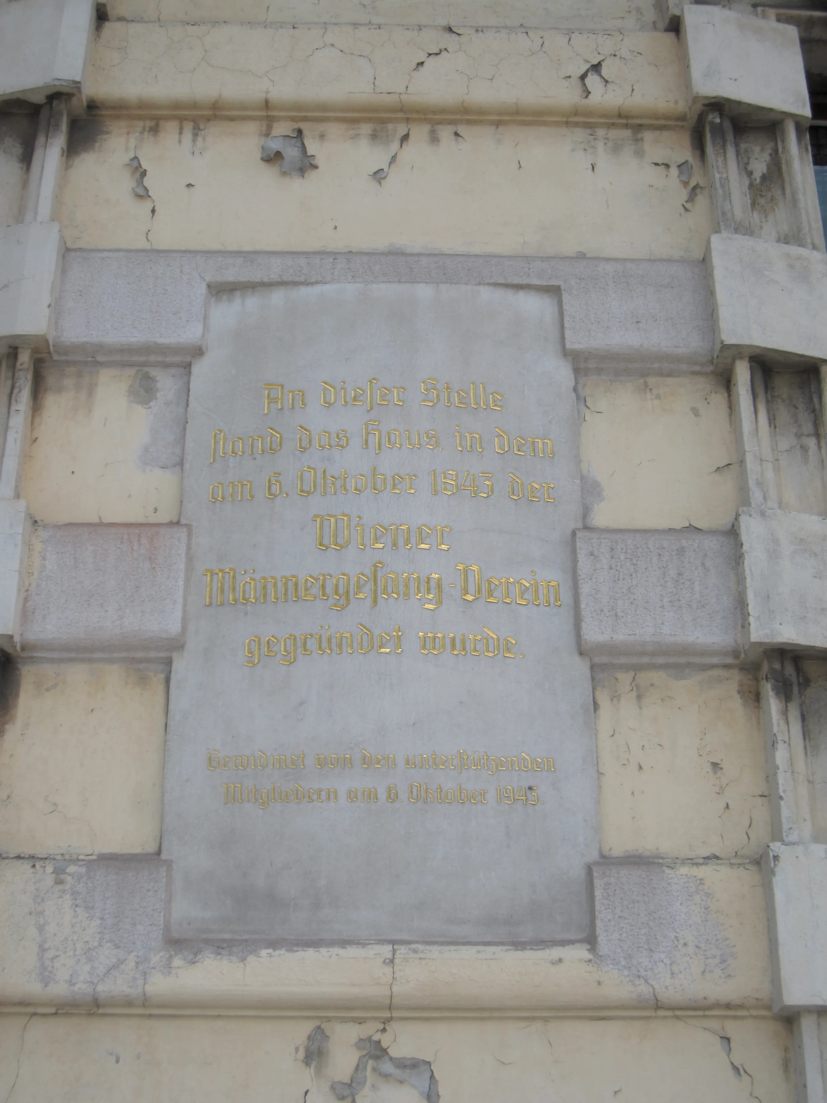 Placa conmemorativa con letras doradas en una pared de piedra, inscrita en alemán.