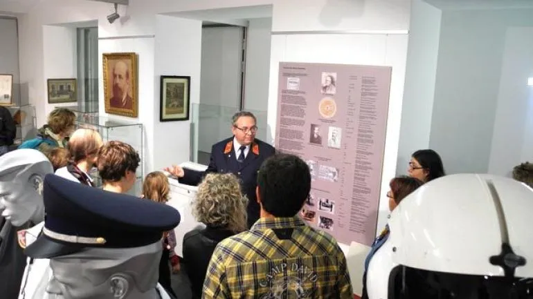 Visitantes viendo una exposición en un museo con paneles informativos y uniformes históricos de rescate