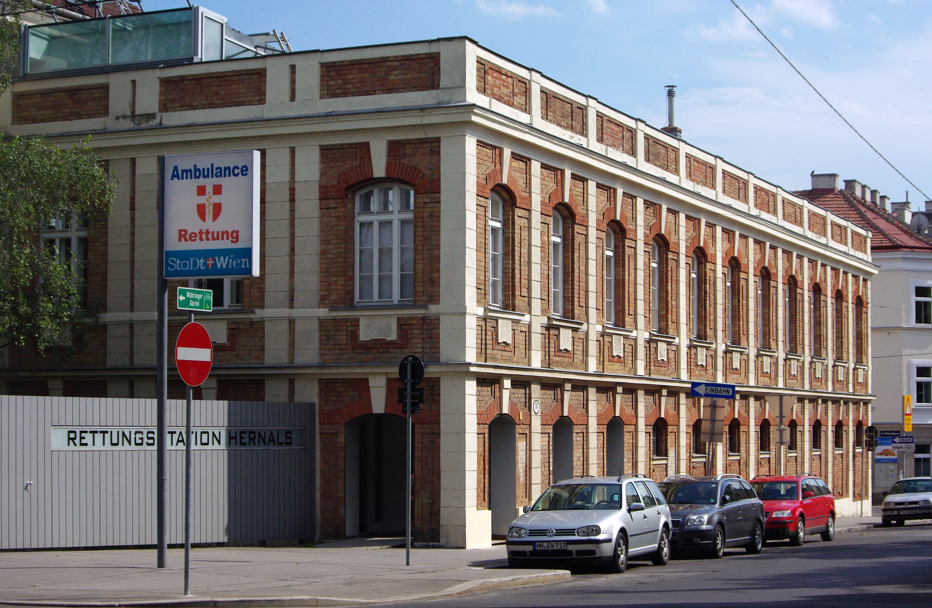 un edificio de ladrillos con ventanas arqueadas y un cartel que dice 'Ambulance Rettung' y 'RETTUNGSSTATION HERNALS'