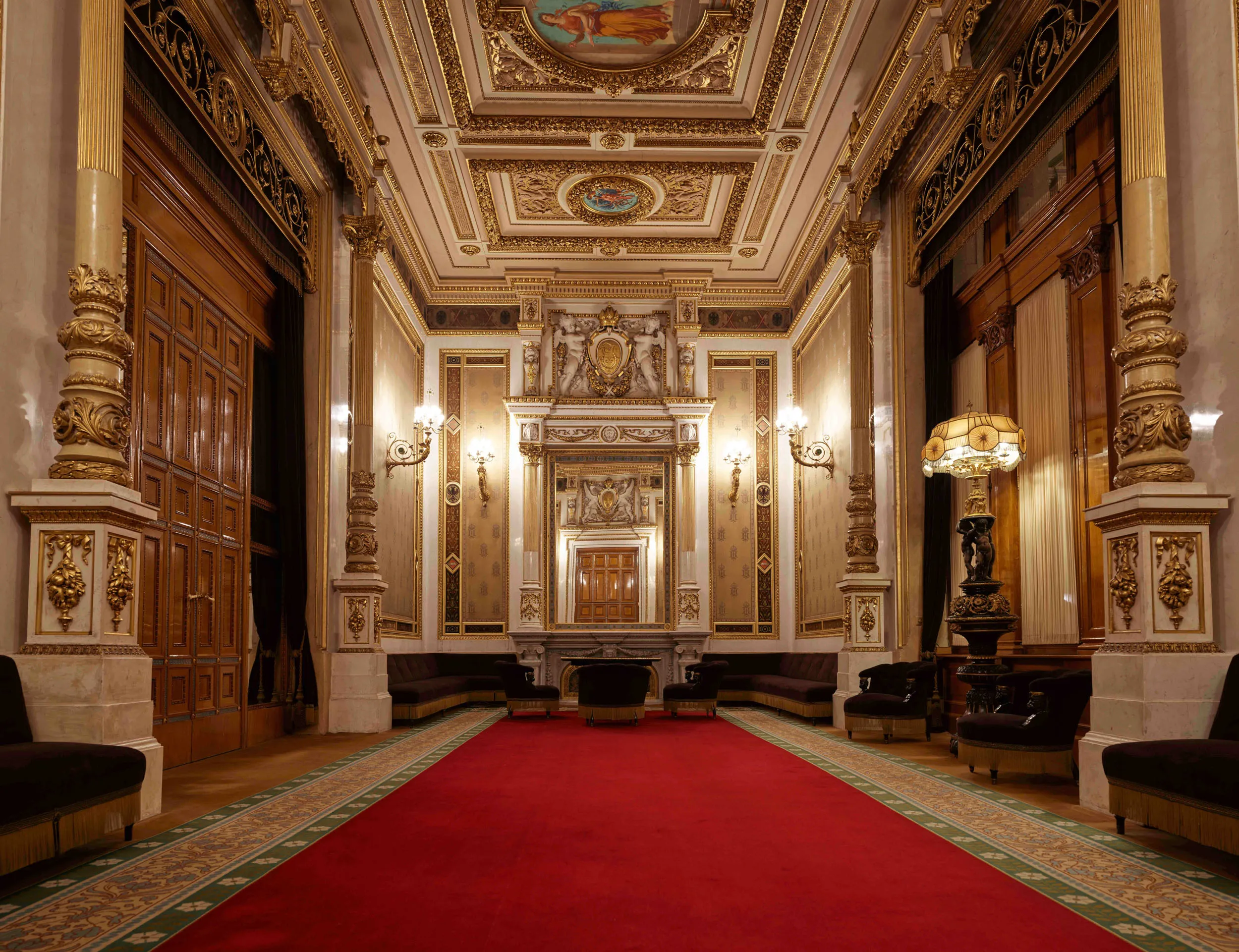 Sierlijke hal met gouden zuilen, rood tapijt en decoratief plafond in de Weense Staatsopera