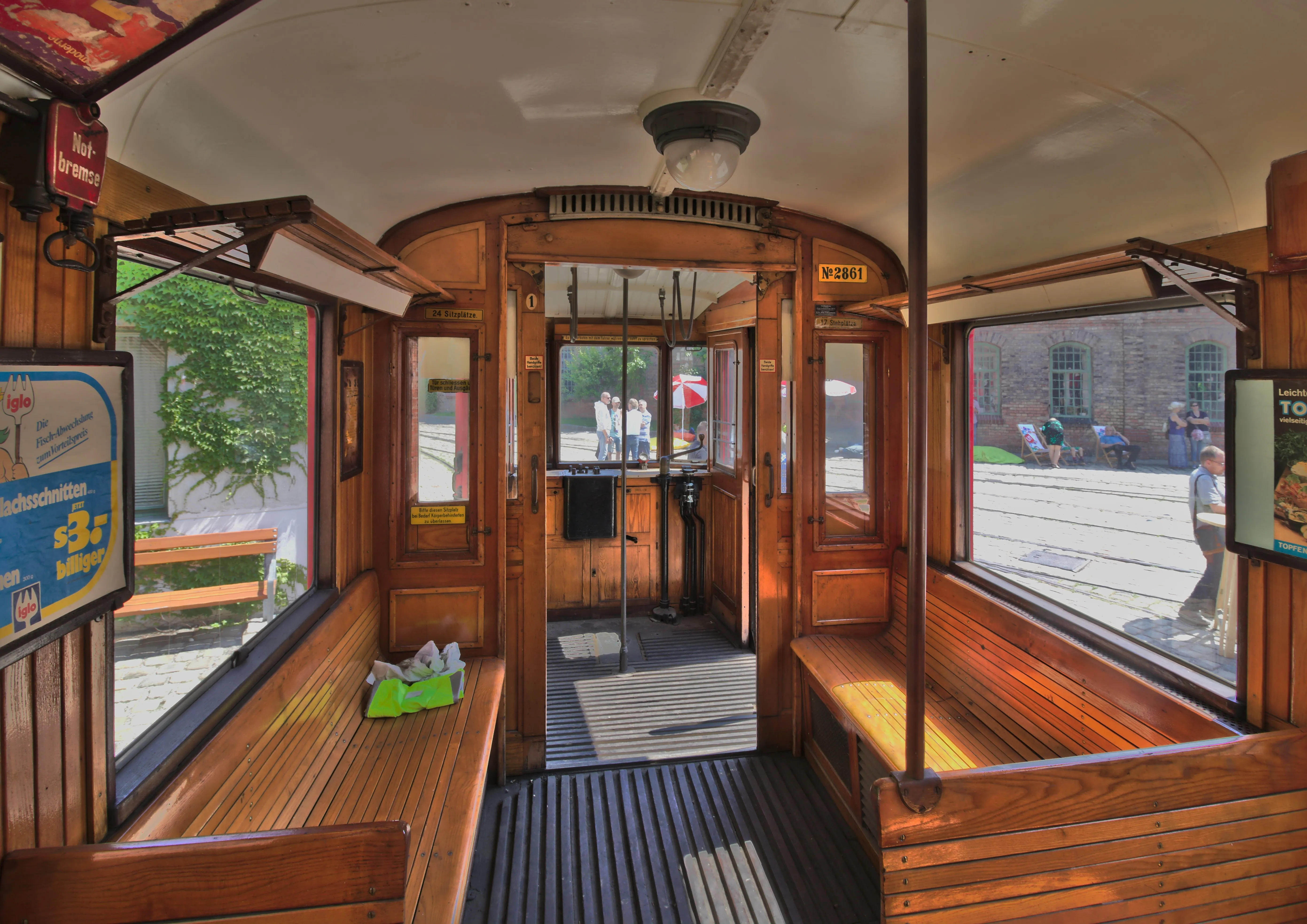 Wnętrze zabytkowego tramwaju z drewnianymi ławkami i zabytkowymi elementami sterowania