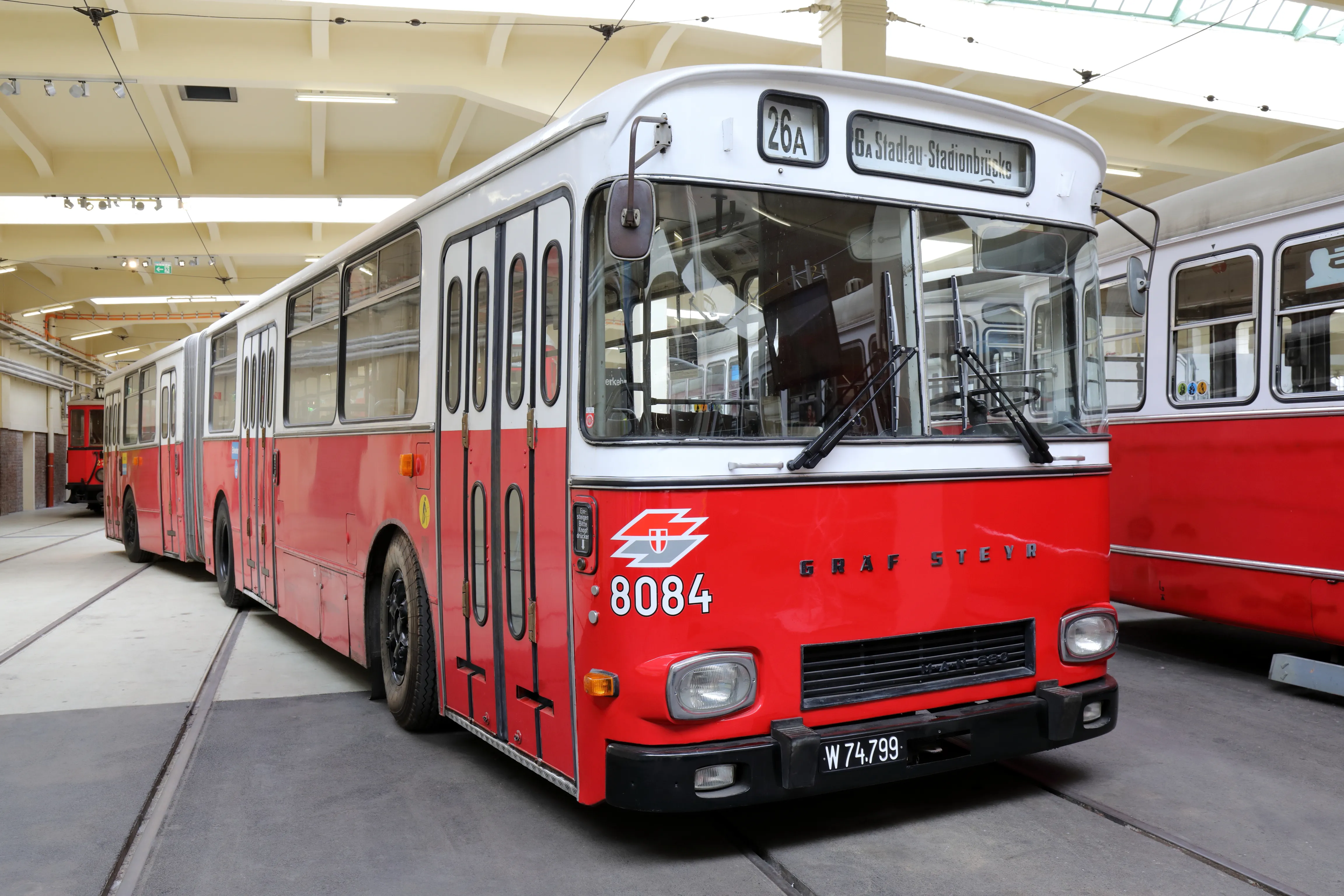 Czerwony i biały autobus przegubowy z numerem 8084, wystawiony w holu muzeum
