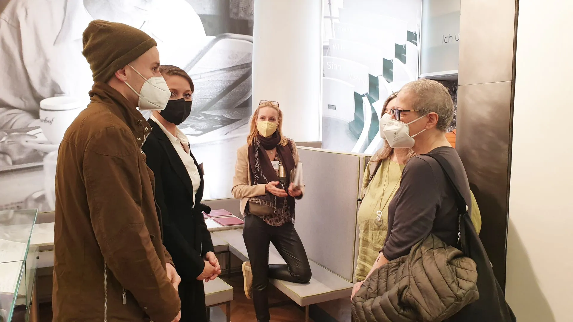 Group of people wearing face masks in a museum gallery with display cases and informational panels.