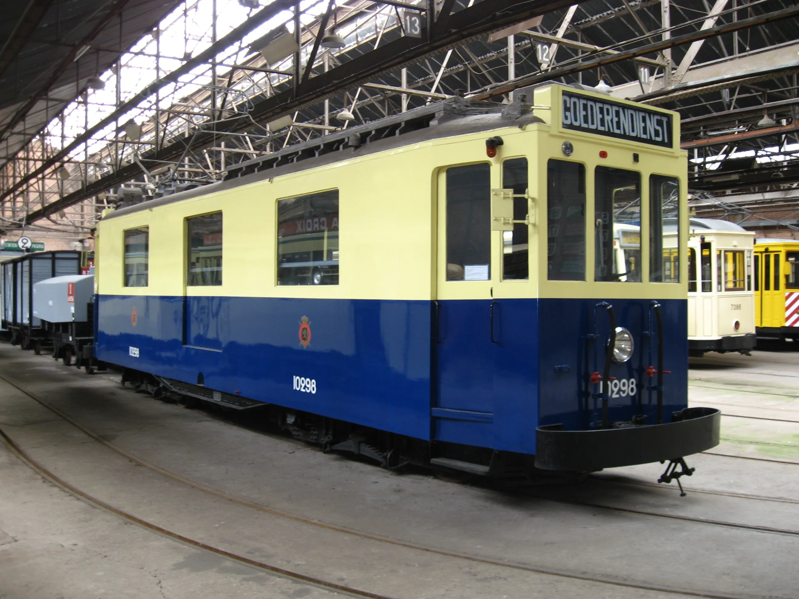 Zabytkowy niebiesko-żółty tramwaj o numerze 1298 z tablicą kierunkową BOEDERDIENST widoczną wewnątrz dużej hali zajezdni