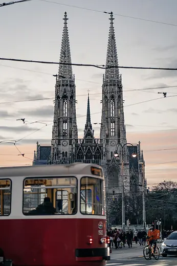 Twin spires of the Votive Church with a red tram in the foreground