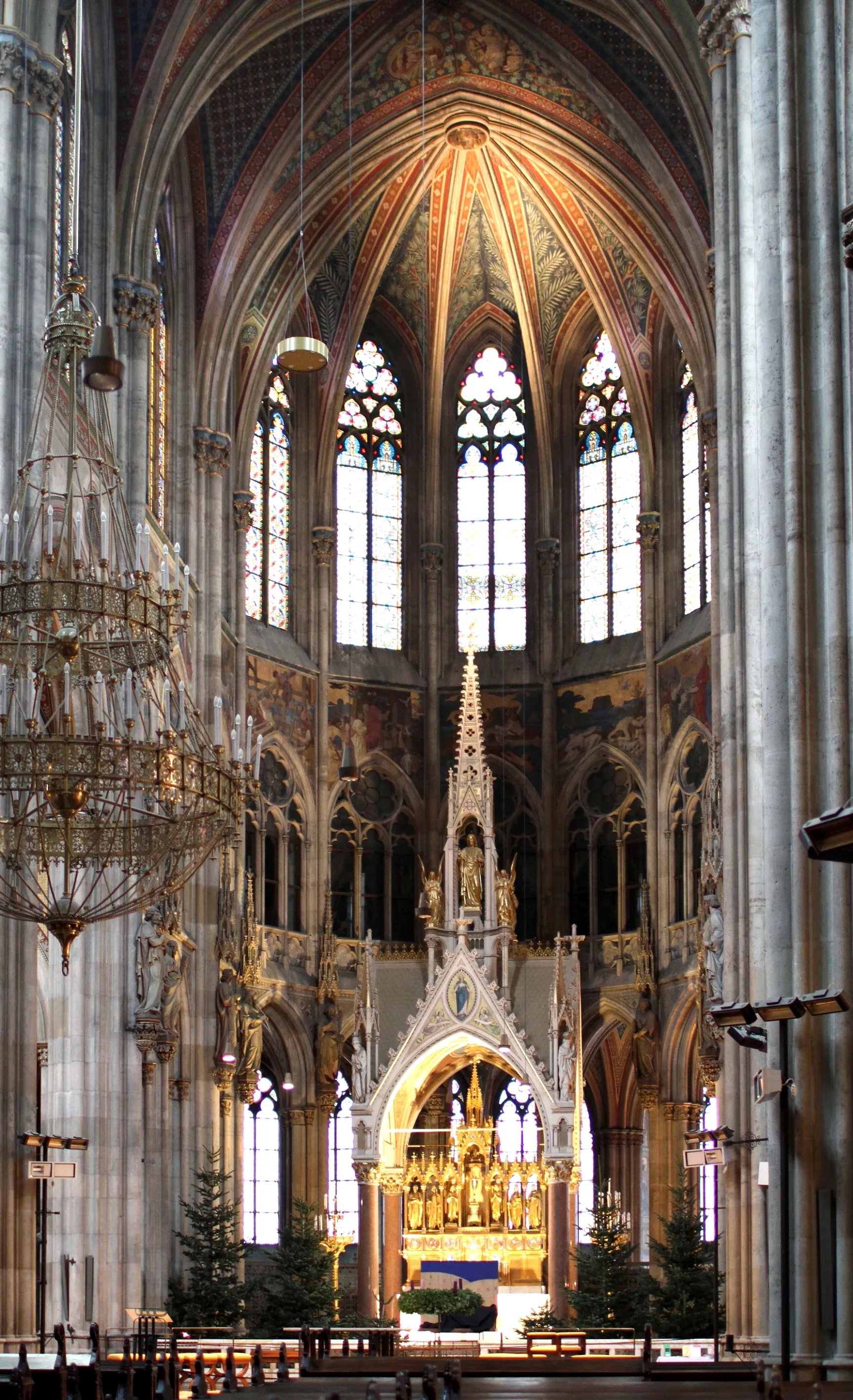 Interior of the Votive Church with high arched ceilings, stained glass windows, and a large chandelier.